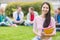 Smiling college student with blurred friends in the park