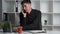 A smiling company consultant in a black shirt sits at a desk in the office and talks to clients