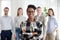 Smiling confident black company employee standing with colleagues at background