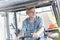 Smiling confident farmer driving tractor at farm