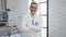 Smiling confident grey-haired young hispanic man scientist standing with a crossed arms gesture in the lab