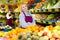 Smiling confident saleswoman of greengrocery store standing among fruits and vegetables