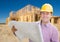 Smiling Contractor Wearing Hardhat Holding Blueprints at Home Co