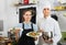 Smiling cook giving to waitress ready to serve salad