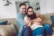 Smiling couple with digital tablet sitting on sofa at home