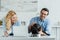 Smiling couple feeding their frenchie dog on kitchen table