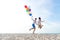 Smiling couple hand holding balloon and jumping together on the beach. Lover romantic and relax honeymoon in summer holiday. Summ
