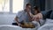 Smiling couple having breakfast in bed in morning