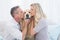 Smiling couple kissing their golden retriever on the couch