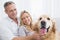 Smiling couple petting their golden retriever on the couch