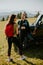 Smiling couple preparing hiking adventure with backpacks by terrain vehicle