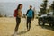 Smiling couple preparing hiking adventure with backpacks by terrain vehicle