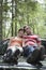 Smiling Couple Sitting On Car Bonnet In Forest