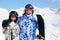 Smiling couple stand with snowboard and skis