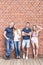 Smiling couples leaning on brick wall