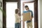Smiling courier delivering parcel to young woman, delivery servi