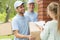 Smiling couriers in blue uniforms and young women filling up delivery documents