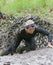 Smiling, crawling, beautiful woman covered with mud crawling