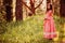 Smiling curly child girl in pink princess dress on the walk in summer forest