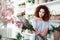 Smiling curly-haired good-looking girl choosing flowers for her masterpiece