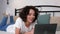 Smiling curly woman uses laptop listens fiends online video call webcam at home