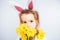Smiling cute baby child in rabbit costumewith a bouquet of yellow daffodils on a white background.