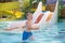 A smiling cute boy has fun in the pool at the aquapark. Activities in the pool. Concept summer vacation, rest, fun