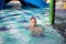 Smiling cute boy has fun in the pool at the aquapark. Activities in the pool. Concept summer vacation, rest, fun