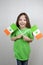 Smiling cute girl in green clothes with flags of Ireland with clover leaves in her hands. Saint Patricks Day celebration