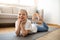 Smiling cute teen european girl in sportswear lies on mat, enjoys workout in living room interior