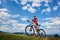 Smiling cyclist in sportswear and helmet standing with cross country bike on top of hill