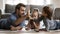 Smiling dad lying on floor carpet with children, enjoying creative activity.