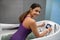 Smiling dark-haired female in purple swimming relaxing in hydromassage bathtub