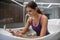 Smiling dark-haired female in purple swimming suit having hydromassage