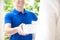 Smiling delivery man in blue uniform delivering parcel box to recipient