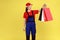 Smiling delivery woman standing with shopping bags in hands, waiting client to deliver parcels.