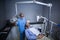 Smiling dentist assistant adjusting light over patients mouth