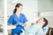 Smiling Dentist In Scrubs Talking To Patient At Clinic