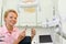 Smiling dentist sits in cabinet of dental clinic