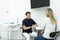 Smiling dentist sits in chair and talks with his client