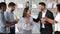 Smiling diverse employees greeting excited female colleague with promotion