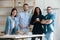 Smiling diverse employees standing in modern boardroom, group portrait