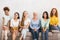 Smiling Diverse Women Sitting On Sofa Over White Brick Wall