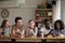 Smiling diverse young women and men using smartphones in cafe.