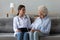 Smiling doctor consulting older woman patient during visit at home