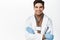 Smiling doctor in medical robe and gloves, looking confident, real professional healthcare worker, white background