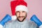 Smiling Doctor in Santa Hat and in protective gloves clenched his hands into a fist. The concept of defeating the coronavirus or