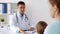 Smiling doctor and woman with baby at clinic