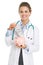 Smiling doctor woman putting dollars banknote in piggy bank