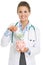 Smiling doctor woman putting euros banknote in piggy bank